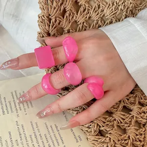 Close-up of pink resin rings set with marble texture on a woven background.