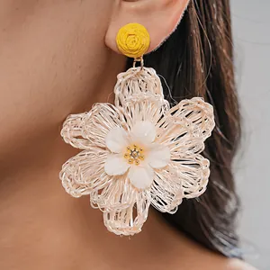 Detailed macro view of handmade woven raffia flower earring showing intricate fiber texture