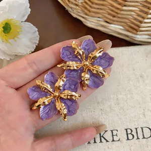 Close-up detail of elegant purple and gold wrinkled flower stud earrings for women