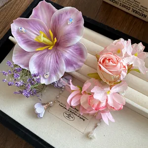 Dettaglio di fermagli per capelli con fiori in tessuto e nappe di perle in una scatola