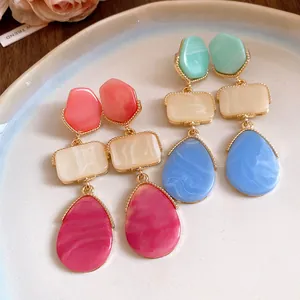 Vue détaillée de boucles d'oreilles vintage en résine avec bordure en métal doré.