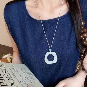 Dettaglio della collana con ciondolo geometrico in acrilico e cordino in pelle su abito blu