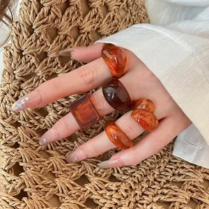 Close-up view of vintage amber resin ring set worn on hand against straw background