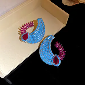 Dettaglio di eleganti orecchini a lobo ad ala con turchese e zircone rosso in confezione.