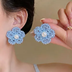 Elegantes pendientes de flor de cuentas azul claro con una perla central en una modelo