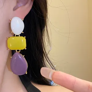 Close-up of retro resin drop earrings with white yellow and purple geometric stones