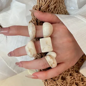 Detailed view of cream marble-textured resin ring set with various geometric shapes