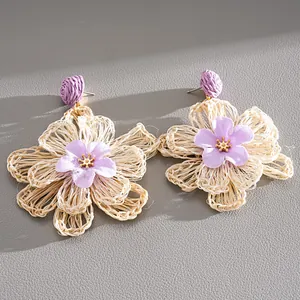 Detailed view of hand-woven raffia flower earrings with purple fabric petals.
