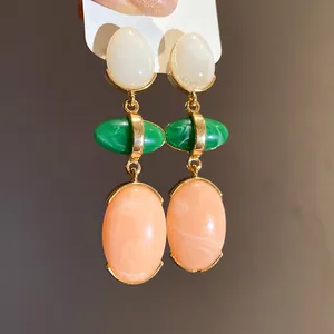 Detailed view of vintage resin drop earrings with white, green and peach oval pendants
