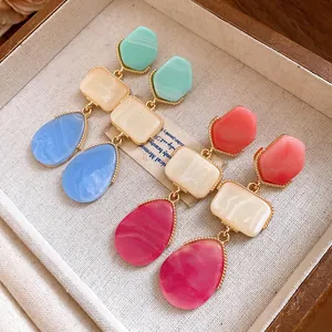 Gros plan de boucles d'oreilles pendantes en résine vintage avec pierres géométriques colorées