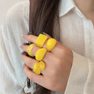 Set of five vibrant yellow chunky resin rings in geometric shapes worn on a hand