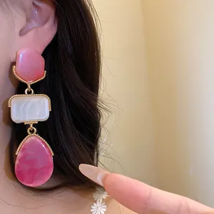 Détail de boucles d'oreilles rétro en résine avec étages géométriques rose et blanc