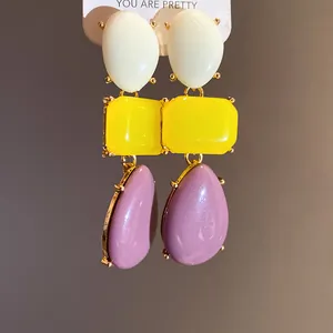 Close-up detail of vintage resin geometric drop earrings in white, yellow, and purple shades