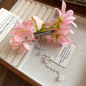 Dettaglio dei fiori in tessuto rosa e nappa di perle su un fermaglio per capelli