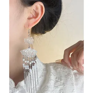 Close-up of white lotus and fan tassel earrings worn with traditional Chinese attire
