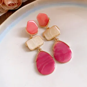 Vue macro de boucles d'oreilles pendantes en résine style cour avec texture marbrée