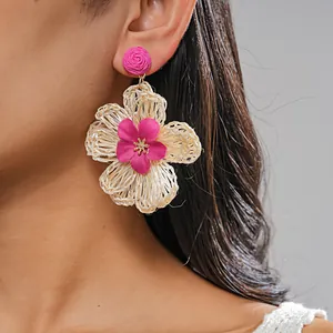 Close-up of handmade raffia woven flower earrings with pink fabric petals for summer