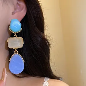Gros plan de boucles d'oreilles élégantes en résine avec des cadres dorés vintage.