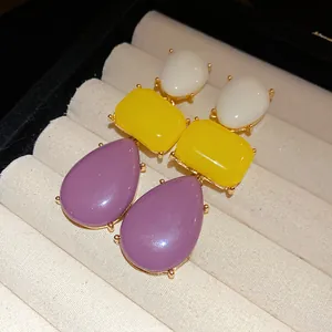 Detail view of vintage resin drop earrings with purple, yellow and white stones.