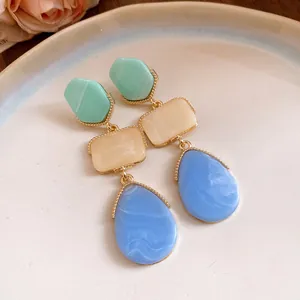 Détail de boucles d'oreilles vintage en résine avec pierres vertes, beiges et bleues