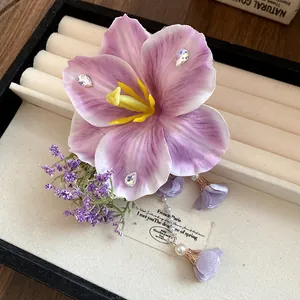 Primo piano di un'elegante clip per capelli a fiore viola con nappe di perle e cristalli.