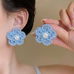 Primer plano de pendientes de flores con cuentas azul claro y perla en modelo