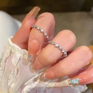 Close-up of silver star zircon open rings worn on fingers with lace sleeve detail