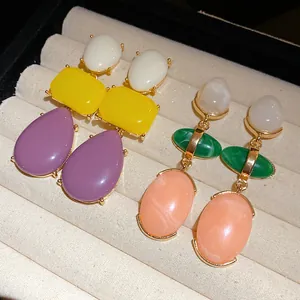 Macro view of vintage-style colorful resin drop earrings showcased on a velvet tray.