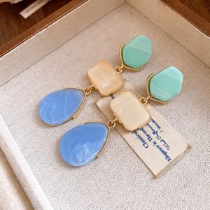 Gros plan sur des boucles d'oreilles vintage en résine avec segments multicolores et dorés