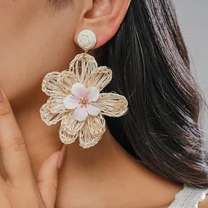 Close-up of handmade raffia woven flower earring worn by a model in vacation style