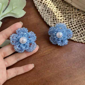 Primer plano de elegantes pendientes de flores con cuentas azules y perla sintética blanca