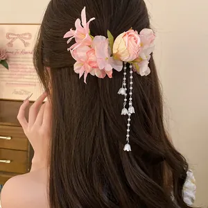 Dettaglio di un fermaglio per capelli con fiori rosa in tessuto e nappe di perle