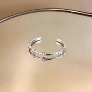 Elegant silver open ring with delicate daisy floral patterns in a detailed macro view