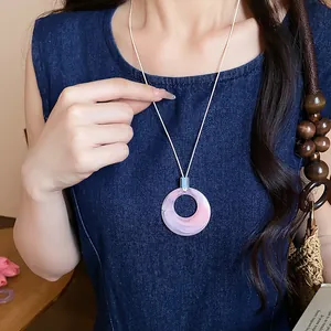 Vista dettagliata della collana con pendente circolare in acrilico rosa e bianco