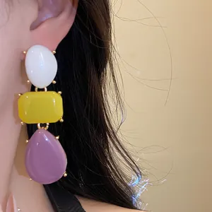 Detail shot of vintage resin drop earrings with white, yellow, and purple shapes.