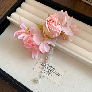 Primo piano della molletta per capelli con fiori rosa, nappe di perle e mughetto per lei