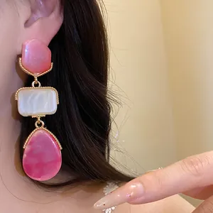 Détail de boucles d'oreilles pendantes vintage en résine rose et blanche