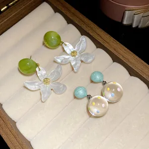 Detailed view of flower and polka dot resin stud earrings in a jewelry box