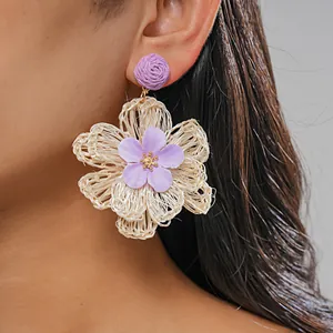 Close-up of handmade raffia woven flower earring with purple fabric petal detail