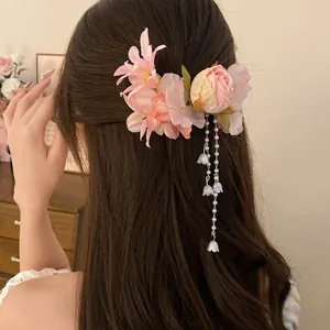Elegante fermaglio per capelli con fiori di stoffa rosa e nappe di perle sui capelli.