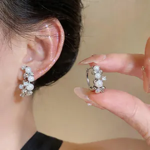 Close-up of elegant silver hoop earrings with white pearls and sparkling cubic zirconia.