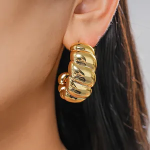 Detaillierte Nahaufnahme eines goldenen Creolen mit Rippen und glänzendem Metallfinish