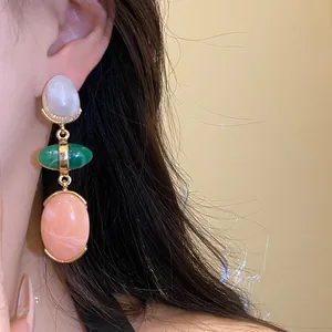 Close-up of vintage resin drop earrings with white, green, and pink oval pendants.
