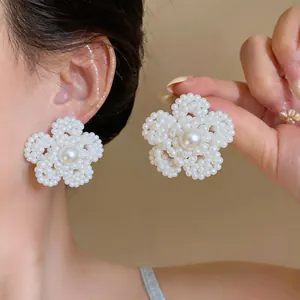 Primer plano de elegantes pendientes de botón con forma de flor y centro de perla