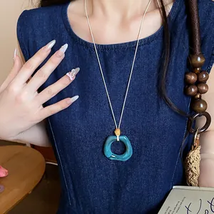 Primo piano di una collana geometrica in acrilico indossata su un abito di jeans.