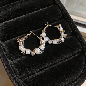 Close-up of elegant pearl and zircon hoop earrings in a black velvet jewelry box