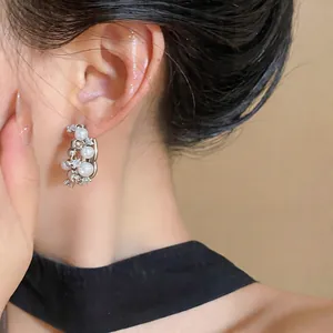 Close-up detail of silver needle geometric earring with pearls and zircons on model ear