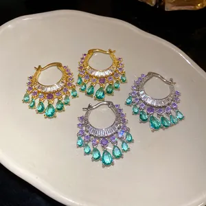 Detailed view of luxury zircon hoop earrings with teal teardrop pendants and purple stones.