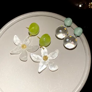 Detailed macro shot of forest-style resin flower earrings and clear polka dot ball pendants