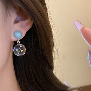 Detailed close-up showing blue resin drop earrings with colorful polka dots worn on ear
